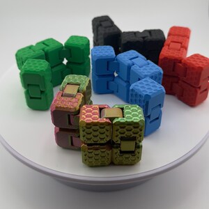 May include: A set of six fidget toys in various colors, including green, blue, red, and iridescent. The toys are made of plastic and have a honeycomb pattern. They are designed to be twisted and turned, providing a tactile and sensory experience.