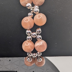 Beautiful handmade Art Deco style beaded bracelet made with natural peach moonstone beads and silver glass accents in a unique X pattern