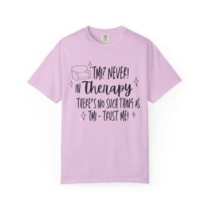 May include: A light purple t-shirt with the text "TMI? NEVER! IN Therapy THERE'S NO SUCH THING AS TMI - TRUST ME!" in black. The shirt has a crew neck and short sleeves.