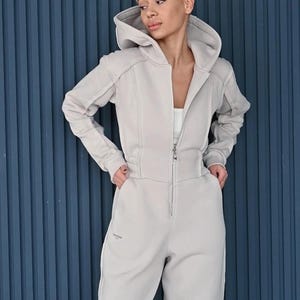 Beige cotton jersey women's jumpsuit, comfortable casual one piece with hood, zipper front overall, relaxed fit lightweight loungewear with pockets