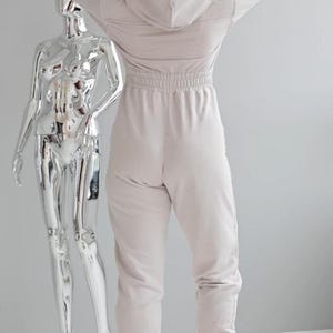 Beige hooded jersey jumpsuit, women's cotton one piece with back view, comfortable casual overall with elastic waist, lightweight leisure outfit