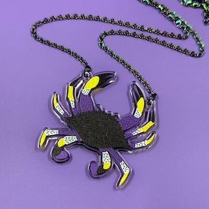 May include: A purple and yellow crab pendant necklace with a black iridescent chain.