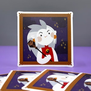 May include: A sticker featuring a cartoon character with white hair, a red and gold outfit, and a staff. The character is in a gold frame against a purple background with gold stars.