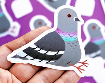 Könnte beinhalten: Ein grauer Taubenaufkleber mit weißen Streifen und einem regenbogenfarbenen Hals in Lila, Blau und Grün. Der Aufkleber hat einen weißen Umriss und befindet sich auf einem violetten Hintergrund.