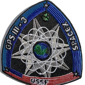 May include: Embroidered patch with a triangular shape, featuring the text "GPS III-3" and "SPACEX". The design includes a stylized atom with a globe at its center, surrounded by stars and the text "USSF". The patch has a black background with blue, white, and red accents.
