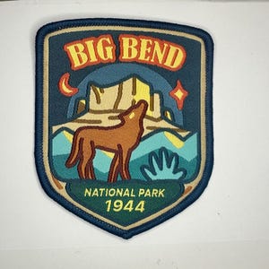 Könnte beinhalten: Ein blauer und brauner gestickter Aufnäher mit den Worten "BIG BEND NATIONAL PARK 1944". Der Aufnäher zeigt ein stilisiertes Bild eines Wolfes, der vor einer Bergkette zum Mond heult.