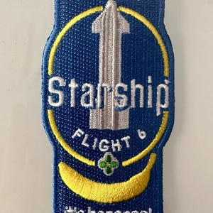 Puede incluir: Un parche bordado azul y amarillo con el texto "SpaceX Starship Flight 6 it's bananas!" y una ilustración de cohete blanco.