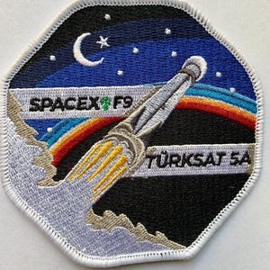 Könnte beinhalten: Gestickter Aufnäher mit einem Raketenstart mit einem Regenbogenbogen vor einem sternenklaren Nachthimmel. Der Aufnäher enthält den Text "SPACEX F9" und "TÜRKSAAT 5A" in weißer Schrift, mit einem Mond und Stern.
