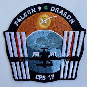 Peut inclure: Un écusson brodé noir et blanc avec le texte "FALCON 9 DRAGON CRS-17". L'écusson représente une image stylisée d'une fusée qui décolle vers la Terre, avec la Station spatiale internationale au premier plan.