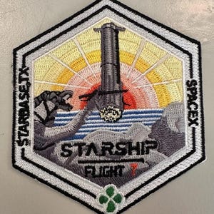Könnte beinhalten: Gestickter Aufnäher mit einer Raketenstartszene und dem Text "STARBASE TX SPACEX STARSHIP FLIGHT 7". Das Design zeigt eine Rakete, das Meer und einen Sonnenaufgang in Gelb, Orange und Blau. Der Aufnäher hat einen schwarzen, weißen und silbernen Rand.