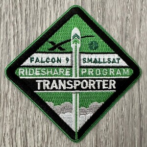 May include: A green and black embroidered patch with the text "Falcon 9 SmallSat Rideshare Program Transporter".
