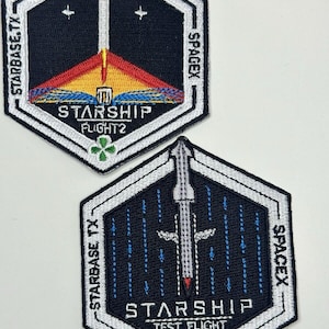Puede incluir: Dos parches bordados con el logotipo de la nave espacial SpaceX. El parche superior es negro con un contorno blanco y tiene el texto "Starship Flight 2" y "SpaceX". El parche inferior es negro con un contorno blanco y tiene el texto "Starship Test Flight" y "SpaceX".