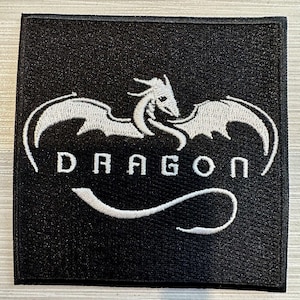 以下が含まれることがあります： 白いドラゴンと「DRAGON」という文字が白で刺繍された黒いパッチ
