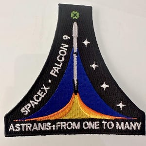 May include: A black, blue, yellow, and orange embroidered patch with a white rocket ship and the text "SPACEX - FALCON 9" and "ASTRANIS - FROM ONE TO MANY".
