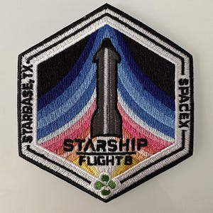 Könnte beinhalten: Ein gestickter schwarzer und weißer Patch in sechseckiger Form. Der Patch zeigt ein stilisiertes Raumschiff mit einem blauen, rosa und gelben Farbverlauf im Hintergrund. Der Text "STARSHIP FLIGHT 8" ist in Weiß gestickt und die Texte "STARBASE TX" und "SPACEX" sind in Weiß an den Seiten des Patches gestickt.