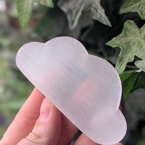 May include: A white selenite crystal shaped like a cloud. The crystal is smooth and polished, with a slightly translucent appearance.