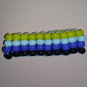 May include: A multi-row bracelet constructed from four horizontal rows of plastic pony beads. The top row is lime green, the second row is light blue, the third row is dark purple, and the bottom row is black, all strung on light blue elastic cord.