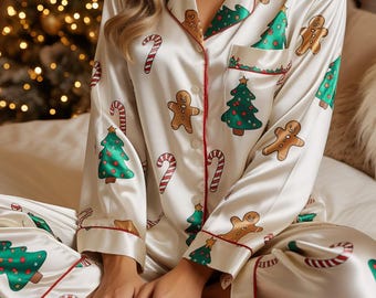 Könnte beinhalten: Cremefarbenes Pyjama-Set mit festlichem Weihnachtsmuster. Das Set zeigt grüne Weihnachtsbäume, Lebkuchenmänner und rot-weiße Zuckerstangen. Der Pyjama hat rote Paspeln und ist aus einem seidigen Material gefertigt.