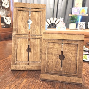 May include: Three wooden display stands with a natural finish. Each stand has a rectangular frame with a vertical slot and a circular opening. The stands are arranged on a wooden surface, showcasing their design and craftsmanship.