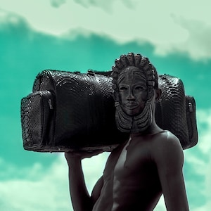 Könnte beinhalten: Eine schwarze Reisetasche mit einer strukturierten, schlangenartigen Musterung. Die Tasche hat zwei Seitentaschen und einen oberen Griff. Der Hintergrund ist ein türkisfarbener Himmel.