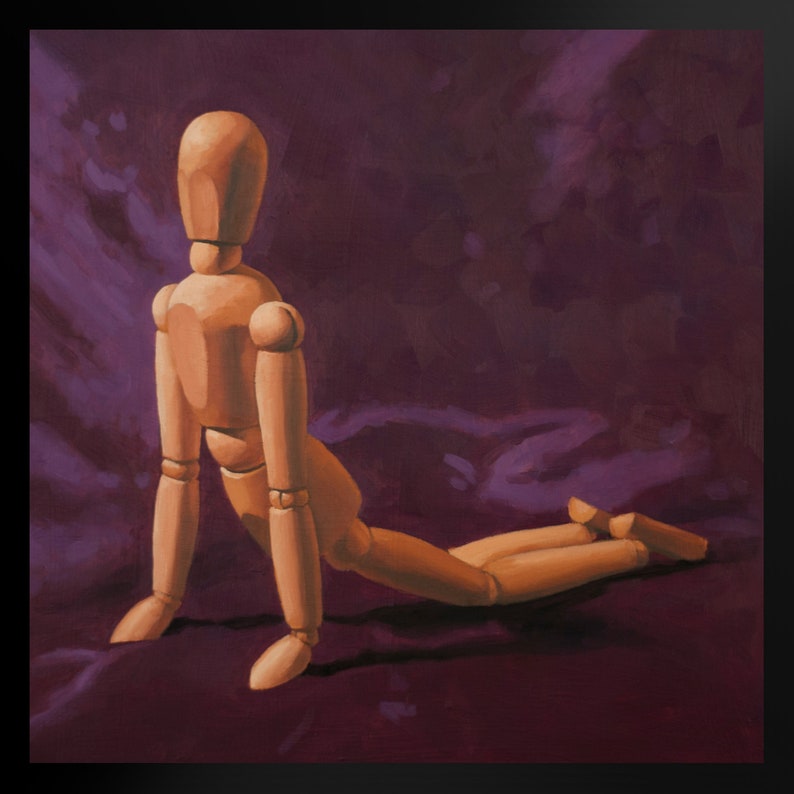 May include: A wooden artist's mannequin posed in a kneeling position on a purple fabric background.