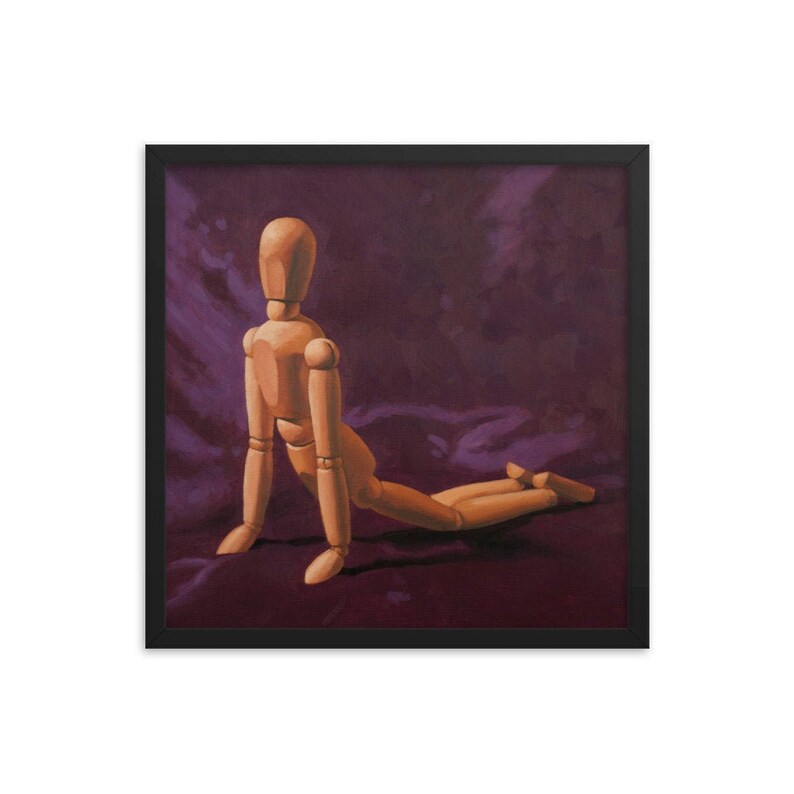 May include: A wooden artist's mannequin posed in a kneeling position on a dark purple fabric background.