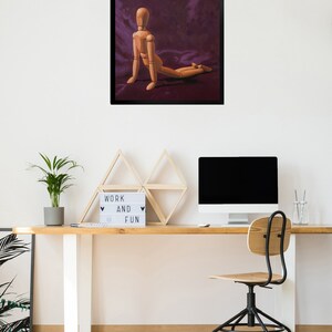 May include: A wooden artist's mannequin posed in a kneeling position on a purple fabric background. The mannequin is made of wood and has a natural finish. The background is a deep purple color and has a soft, velvety texture.