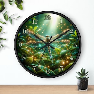 May include: A round wall clock with a black frame. The clock face features a detailed illustration of a dragonfly with shimmering wings, surrounded by lush green foliage and glowing lights. The clock hands are black.