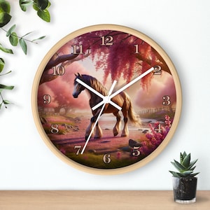 May include: A round wall clock with a white background and black Roman numeral hour markers. The clock face features a brown horse standing in a field of pink flowers. The clock has a wooden frame.