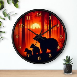 May include: Black round wall clock featuring a forest scene with a sunset and bear silhouettes. The clock has gold numerals and hands, and a black frame. The background shows tall trees and a setting sun, creating a warm, inviting atmosphere.