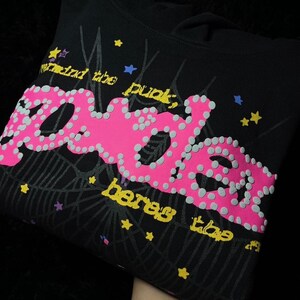 May include: Black hoodie with a pink and gray dotted "spider" graphic. The design includes a spiderweb, stars, and the phrases "meet the punk" and "heres the".