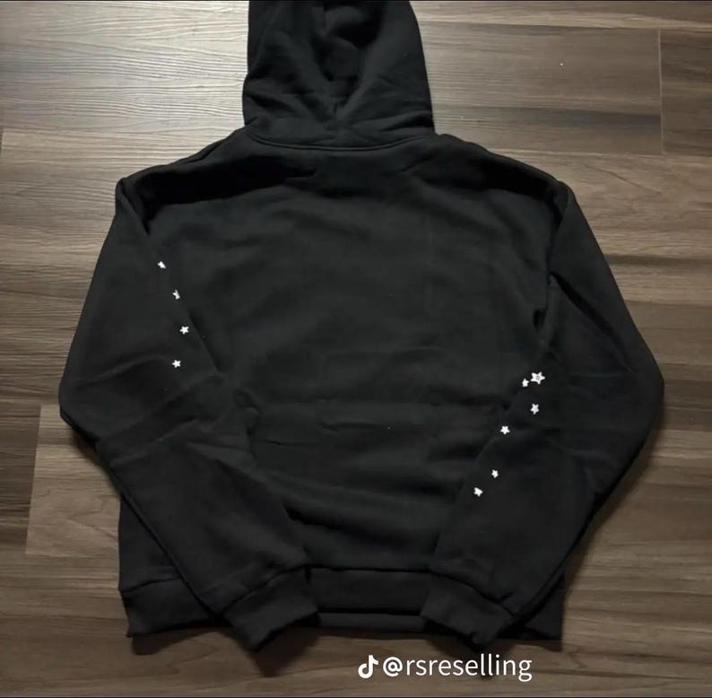 May include: Black hooded sweatshirt with white star accents on the sleeves. The sweatshirt has a drawstring hood and a ribbed hem and cuffs. The text "@rsreselling" is at the bottom of the image.