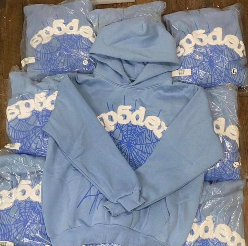 May include: Light blue hoodies with white text and a blue spiderweb design. The word "p5de" is printed across the chest. Several hoodies are visible, some in plastic packaging. The hoodies have a hood and a front pocket.