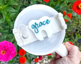 May include: White tumbler lid with a teal tooth charm that says "grace" on it.