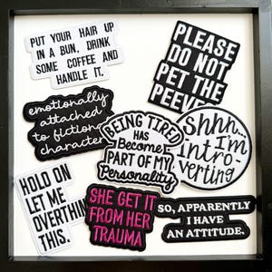May include: A collection of black and white embroidered patches with humorous phrases, including "Put your hair up in a bun, drink some coffee and handle it." and "Please do not pet the peeve."