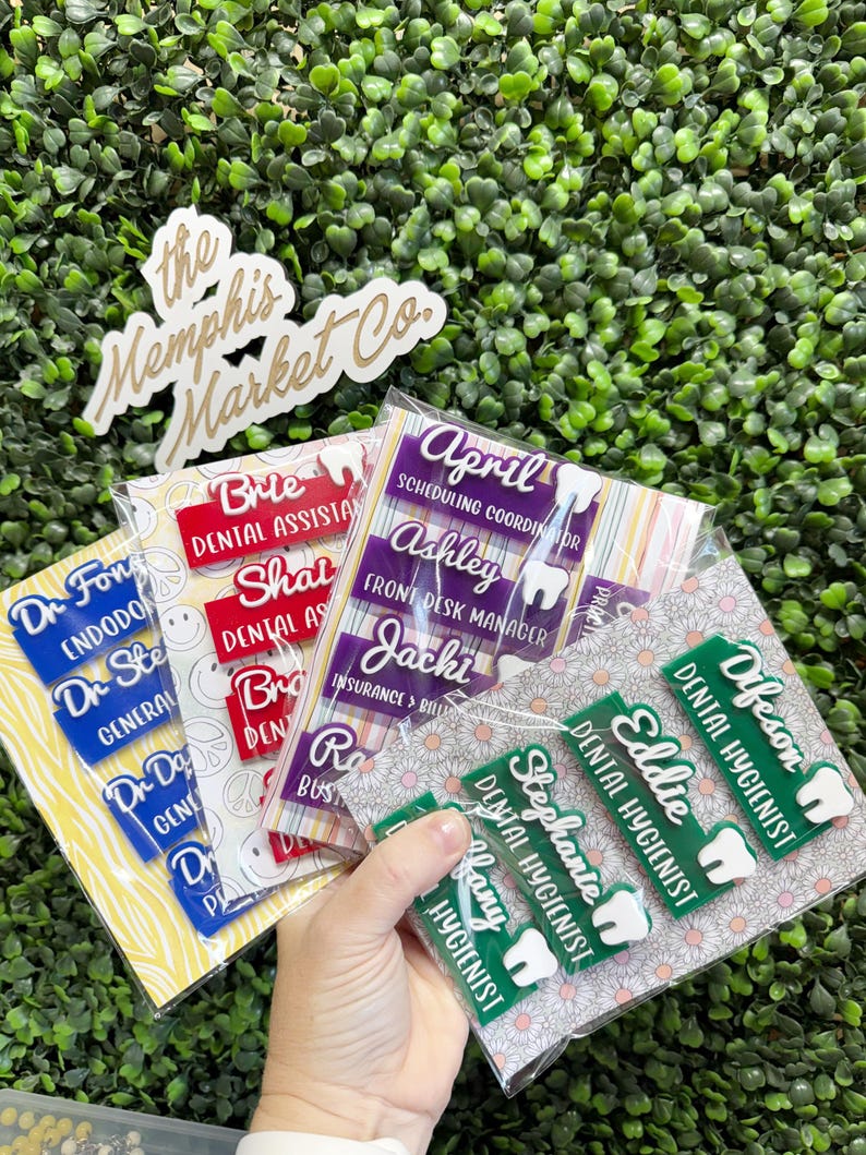 May include: A collection of name badges for dental professionals. The badges are in various colors, including red, purple, and green, with white text. Some badges include a tooth graphic. The Memphis Market Co. logo is also visible.