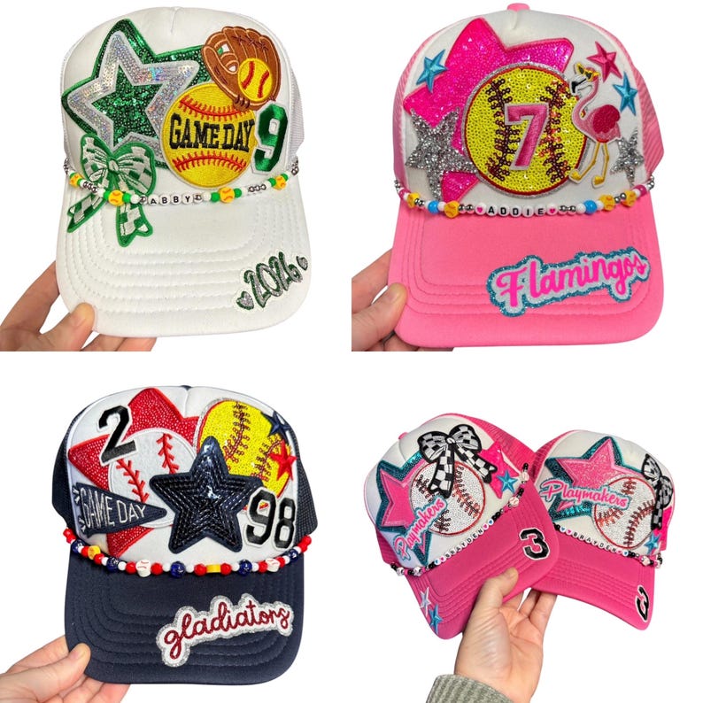 May include: Four baseball caps with decorative embellishments. One white cap has a green star, baseball, and the text "GAME DAY 9". A pink cap features a sequined star, the number "7", and the word "Flamingos". A navy blue cap has the text "GAME DAY" and "98". Two pink caps say "Playmakers".