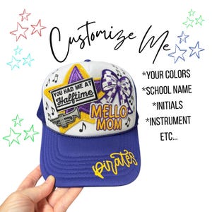 May include: A white and purple trucker hat featuring a yellow star patch, a purple and white checkered bow, a trumpet icon, and the text "YOU HAD ME AT Halftime", "MELLO MOM", and "Pirates". The text "Customize Me" and list items appear.