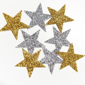 May include: A collection of eight star-shaped patches featuring a textured, glittery surface. Four of the stars are gold and four are silver, arranged in a scattered pattern. Each star has five points and a uniform, sparkling finish throughout.