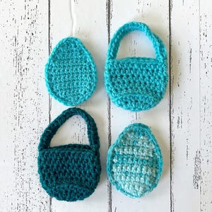 Puede incluir: Cuatro bolsas de ganchillo en colores turquesa y verde azulado. Dos de las bolsas tienen asas y dos son planas.