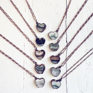 May include: Ten delicate copper necklaces with heart-shaped pendants featuring unique agate slices. Each pendant showcases a different pattern of white, grey, and green agate.