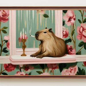May include: A framed painting depicts a capybara with a cigarette, seated on a pink windowsill. A gold candlestick with lit candles sits nearby. The background features a floral wallpaper with pink roses and a light green backdrop.