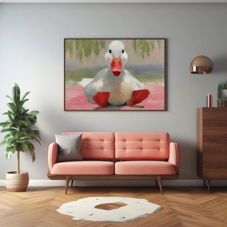 Puede incluir: Pintura enmarcada de un pato blanco con pico y patas rojas. El pato est&aacute; sentado sobre una superficie rosa con un fondo verde y blanco. La pintura se exhibe sobre un sof&aacute; rosa en una sala de estar.