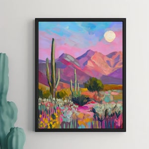 May include: A framed landscape painting depicts a desert scene with mountains, cacti, and wildflowers under a pink and blue sky with a full moon. The artwork uses vibrant brushstrokes and a rich color palette of pinks, purples, yellows, and greens.