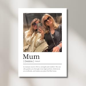 May include: A white print featuring a photograph of two women wearing sunglasses. The word "Mum" is printed in a bold font, followed by a definition. The definition describes a mother as a source of love, strength, and comfort.