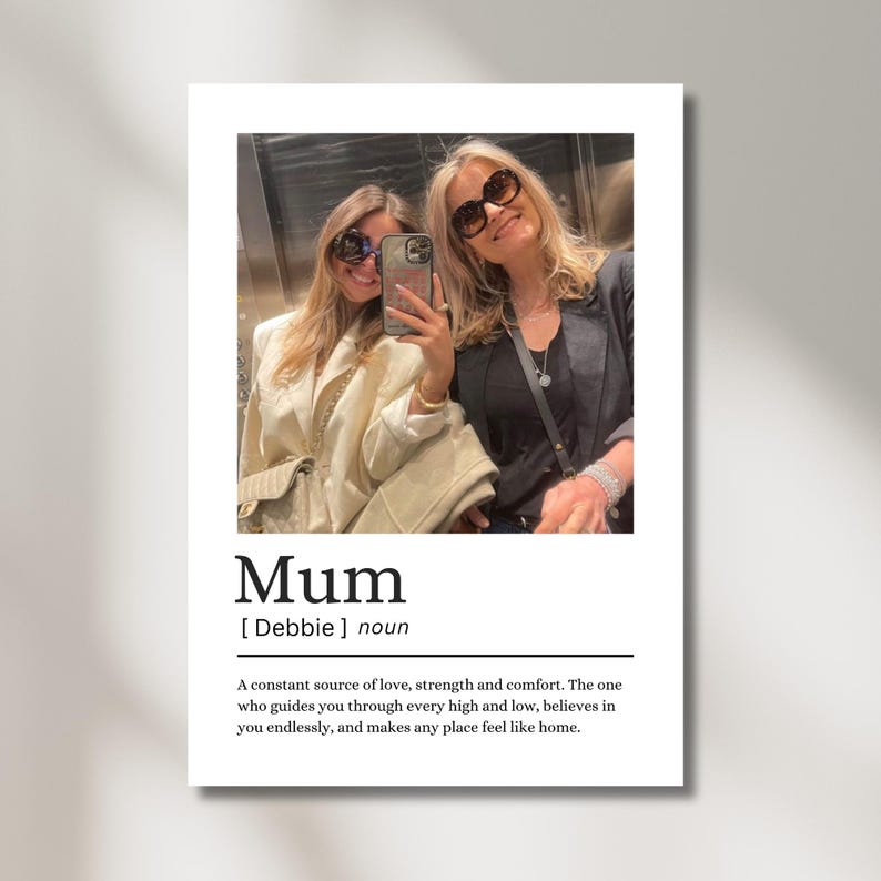 May include: A white print featuring a photograph of two women wearing sunglasses. The word "Mum" is printed in a bold font, followed by a definition. The definition describes a mother as a source of love, strength, and comfort.