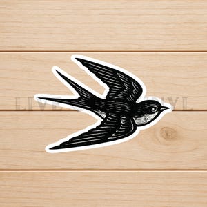 Op de afbeelding: Zwart-wit illustratie van een zwaluw in vlucht. De vogel is afgebeeld met gedetailleerde vleugelveren en een lange, gevorkte staart. Het ontwerp heeft een vintage, houtsnede stijl, met het silhouet van de vogel tegen een witte achtergrond.