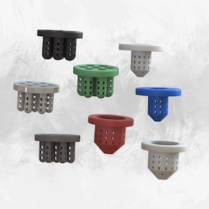 Peut inclure: Diverses crépines d'évier en plastique coloré, en noir, vert, rouge, bleu et blanc. Chaque crépine présente un design perforé et une forme unique, adaptée à une utilisation en cuisine ou en salle de bain.
