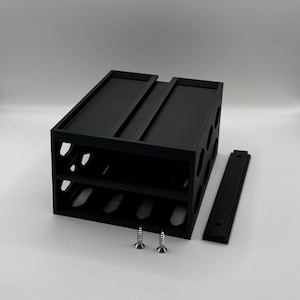 Puede incluir: Un botellero negro de diseño rectangular, con dos niveles para botellas y una balda superior. Incluye una pieza negra separada y dos tornillos plateados. Diseñado para contener varias botellas.
