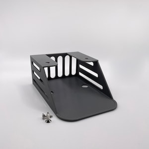 May include: A black metal bracket with a rectangular base and a slotted design. Two screws are included. The bracket has a curved front edge and is designed for mounting.